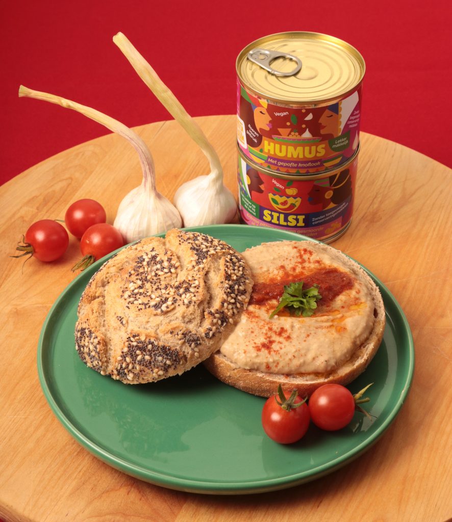 Kleine humus en silsi blik van Mixblik. Brood met humus en silsi op bord.