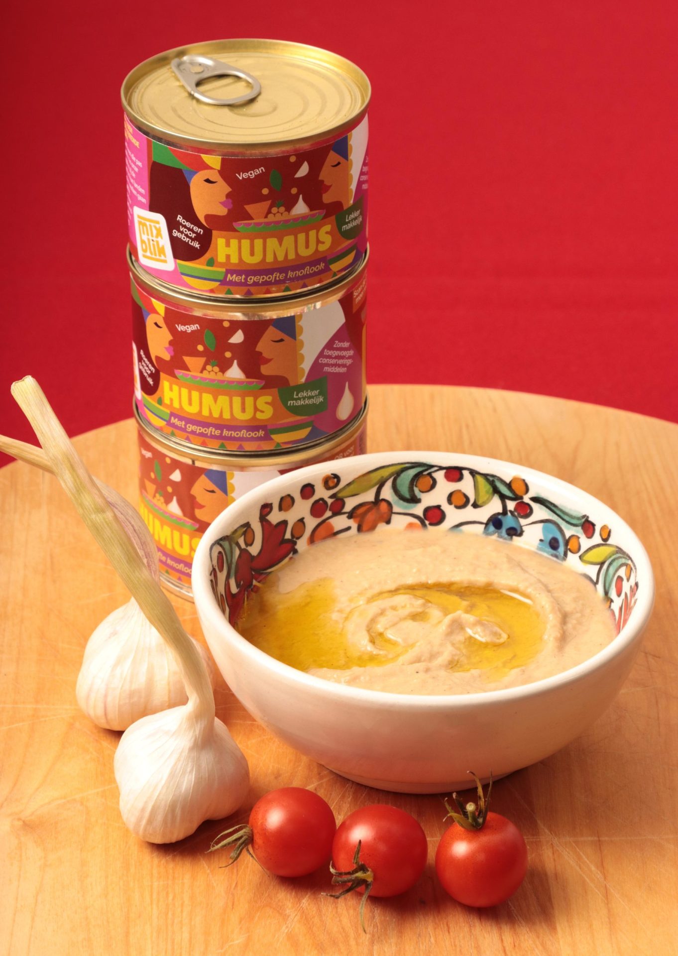 Mixblik kleine humus blikken gestapeld. Op houten tafel met tomaten en uien