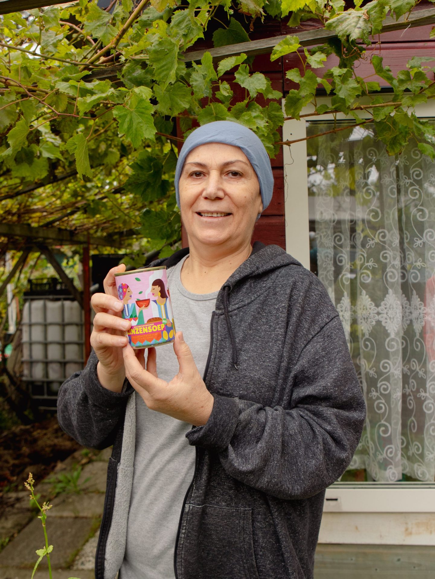 Mixblik vrouw Selde buiten huis met Linzensoep blik in hand