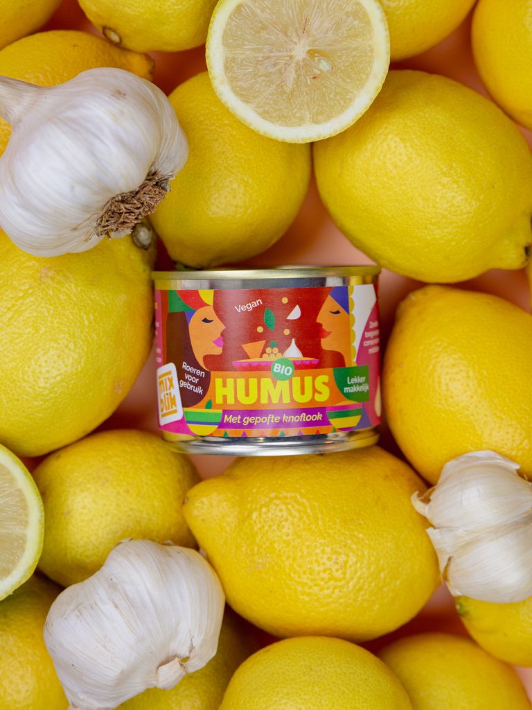 Mixblik humus blik met citroenen en uien op de achtergrond.